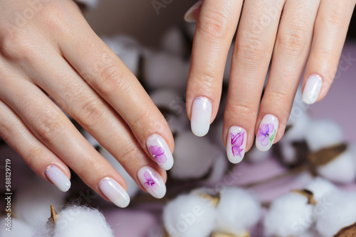 Beautiful manicure with nail design. Female hands on fluffy cotton flowers.