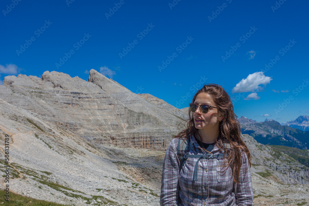 Portrait of young woman with sunglasses and long hair. Scenic landscape on the nature, Mount Latemar, Trentino, Italy. Traveling photography and outdoor sport activity concept Portrait of young woman with sunglasses and long hair. Scenic landscape on the nature, Mount Latemar, Trentino, Italy. Traveling photography and outdoor sport activity concept