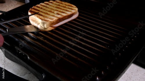 person removing two sandwiches from electric grill
