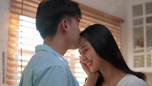 Cute Asian young couple embracing at home.