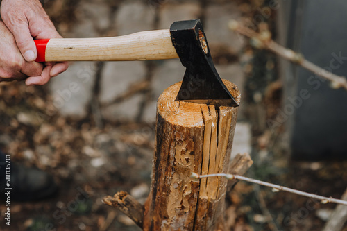 A man, a lumberjack, cuts firewood, logs, trees with an ax in the forest, outdoors, nature.