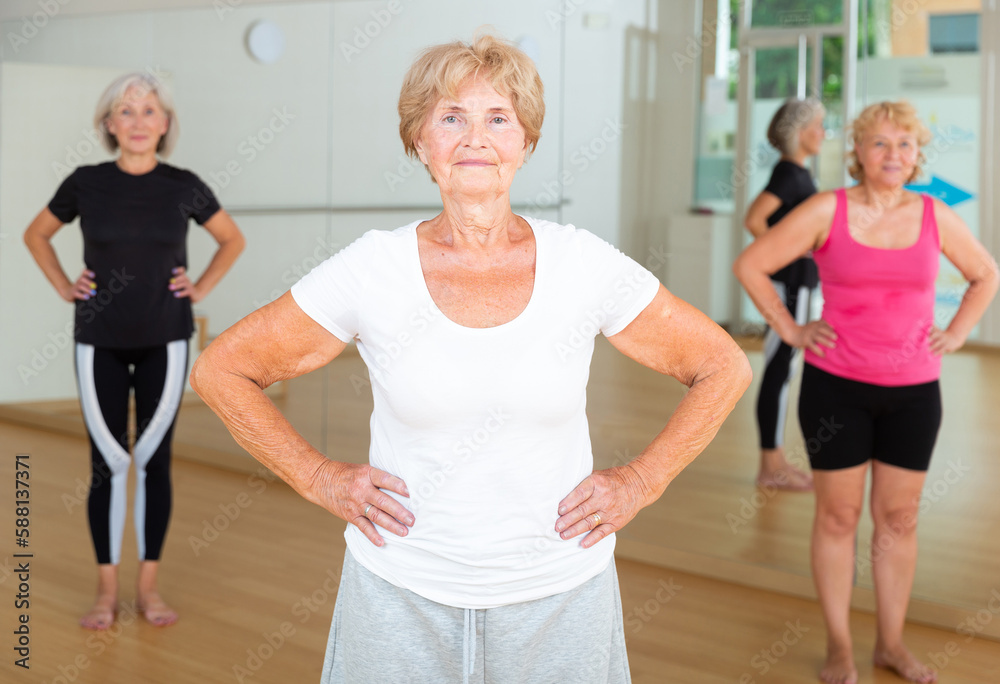 Mature women in sportswear standing in fitness room during their group training.