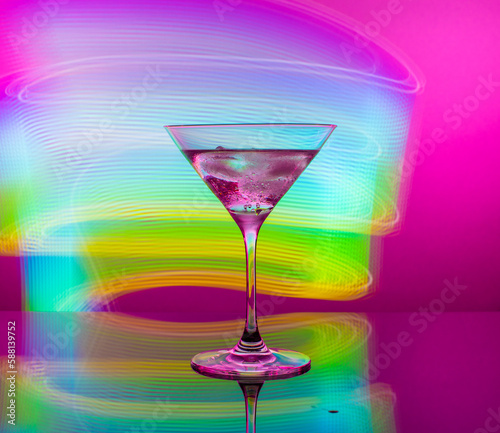Alcoholic martini cocktail in a glass goblet on a background of blue neon lights
