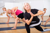 Mature women exercising yoga pose during their group training.