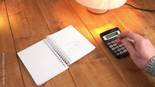 A man calculates on a calculator and writes the result in a notebook.