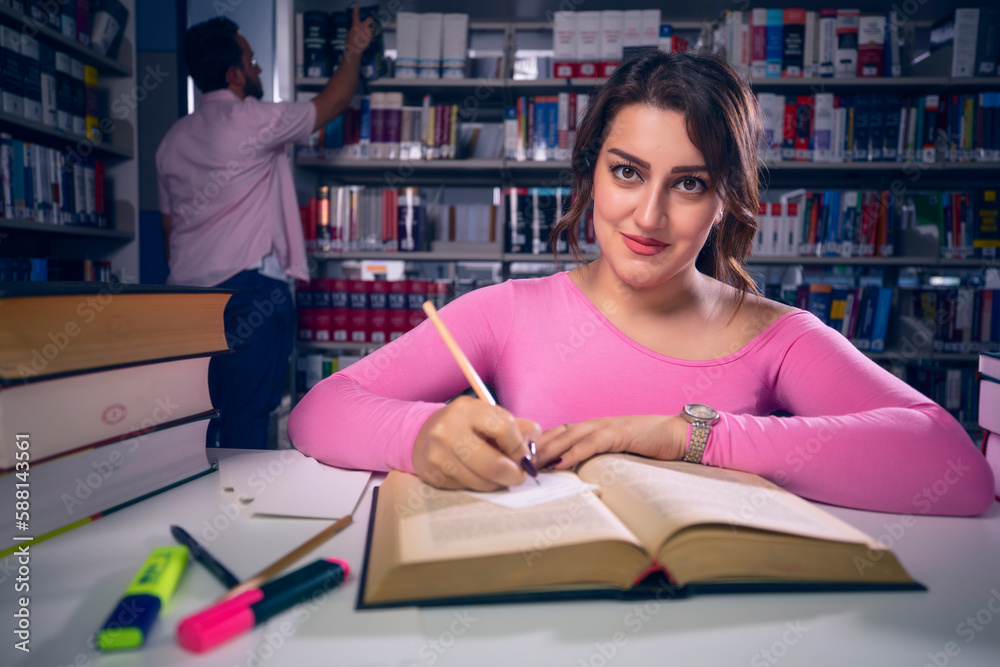Young, beautiful student girl who studies at the library and writes notes. The girl is studying and preparing for the exam. Young, beautiful student girl who studies at the library and writes notes. The girl is studying and preparing for the exam.