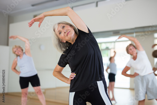 Portrait of mature energetic woman and people practicing active dancing in the studio at a group lesson © JackF