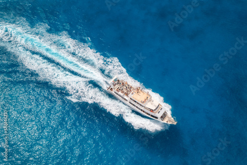 Aerial view of beautiful floating yacht in blue sea at sunny day in summer. Sardinia island, Italy. Drone view of speed boat, sea coast, transparent water. Travel. Tropical landscape. Yachting © den-belitsky