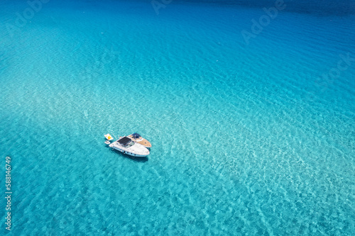 Aerial view of beautiful luxury yacht and boat in blue sea at sunny day in summer. Sardinia island, Italy. Top drone view of speed boat, ocean, azure clear water. Travel. Tropical landscape. Yachting © den-belitsky