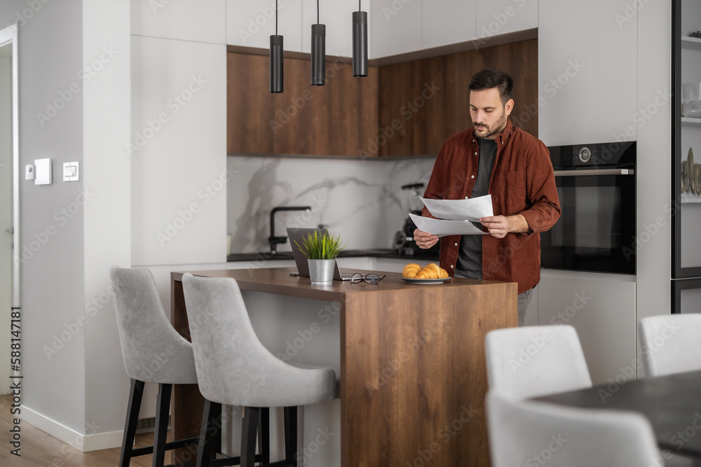 Young man using laptop computer, calculating taxes while working from home office. Paying bills, taxes at home online. Young man using laptop computer, calculating taxes while working from home office. Paying bills, taxes at home online.