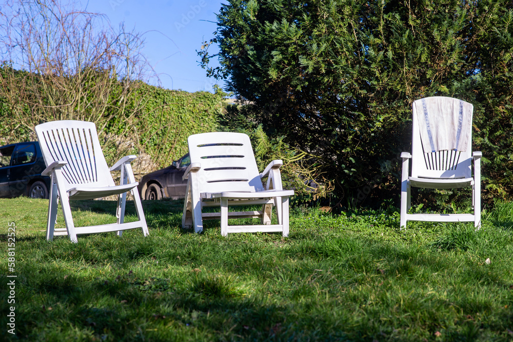 Empty sun loungers on grass in courtyard of house. Places to relax near green tree. Relaxation. Empty sun loungers on grass in courtyard of house. Places to relax near green tree. Relaxation.
