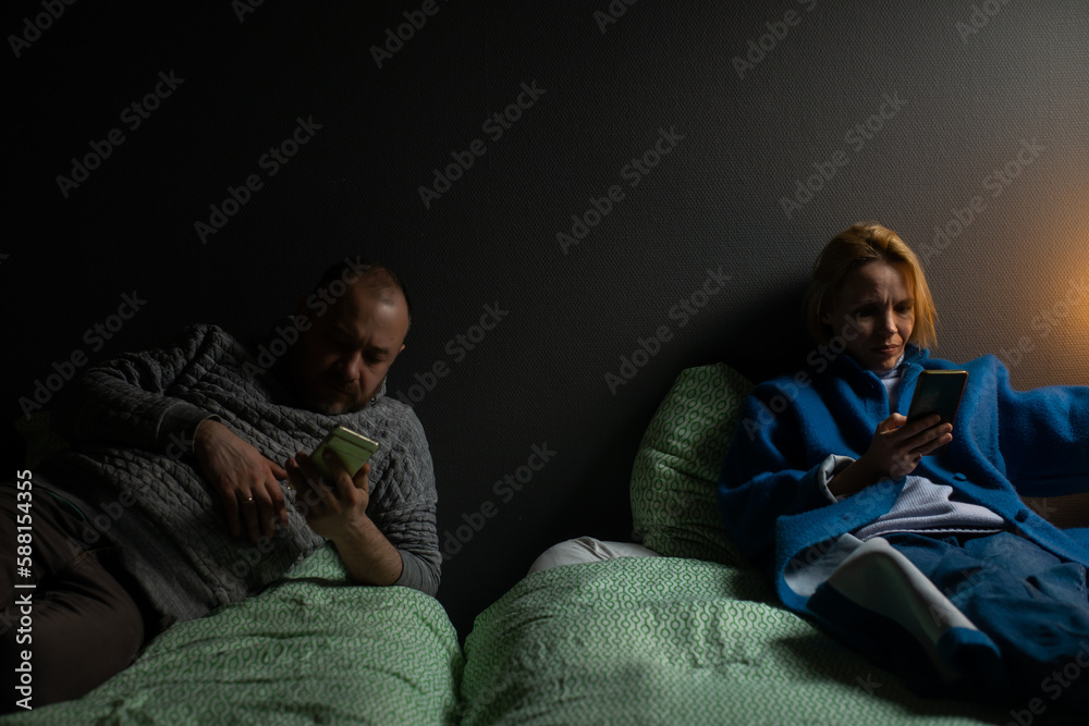 Two bored spouses. Indifference in a couple. Everyone has their own interests. Husband and wife in different beds. Two bored spouses. Indifference in a couple. Everyone has their own interests. Husband and wife in different beds.