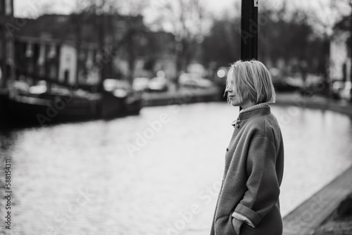 A woman in a long blue coat in the Netherlands. Tourist while traveling in Rotterdam. Black and white photo.
