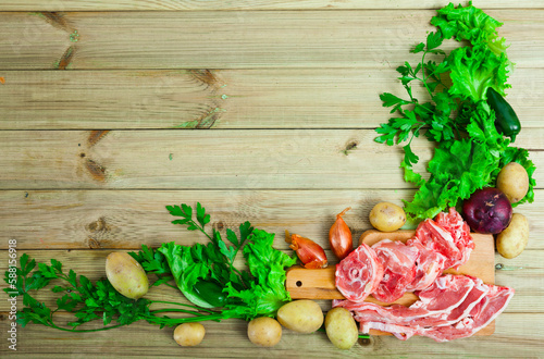 Ingredients for delicious meals. Sliced fresh raw mutton, vegetables, herbs and seasonings on wooden surface