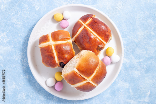 Traditional easter food hot cross buns on white plate with chocolate candy eggs, horizontal, top