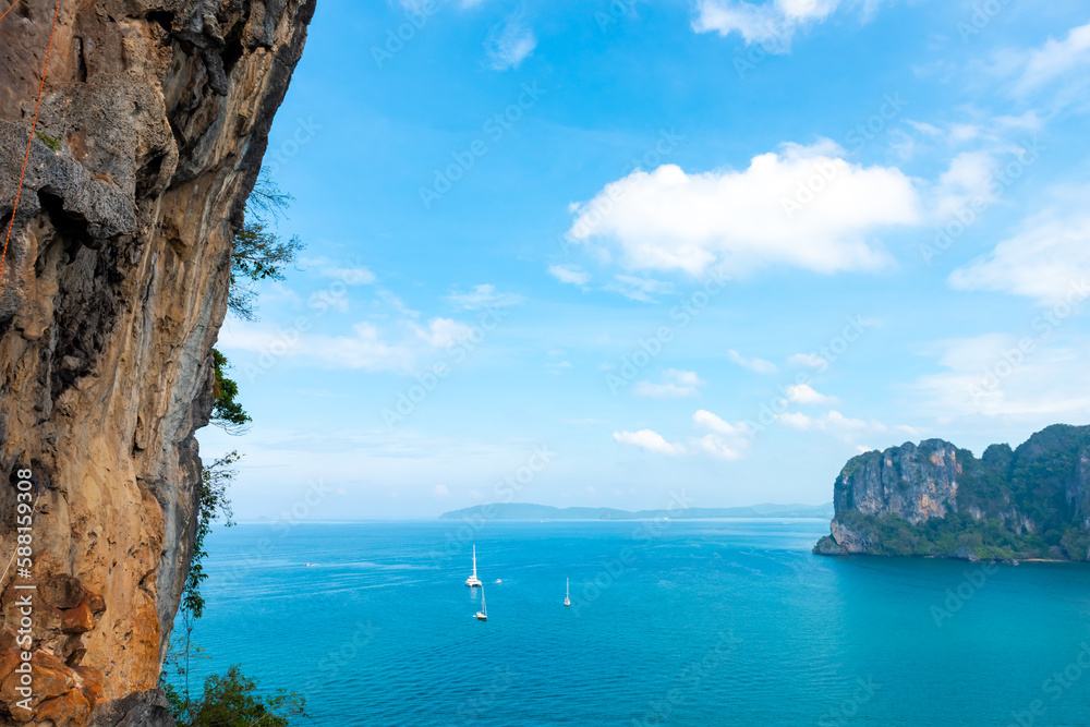 Landscape of the Ocean with tropical island mountain peak in Krabi prefecture, Thailand in sunny day. Beautiful nature of blue sea with tourist yacht boat passing the beach on summer holiday vacation.