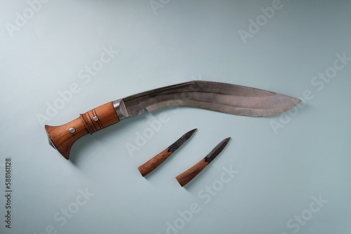 An ancient curved kukri knife on a blue background, small knives with a wooden handle, a place for an inscription photo