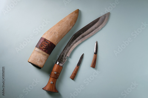 Ancient curved kukri knife on a blue background, small knives with a wooden handle