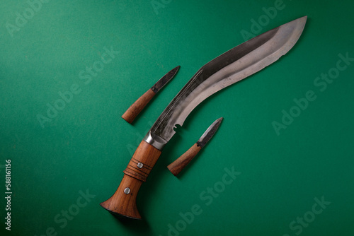 An ancient curved kukri knife and small knives on a green background, a place for an inscription