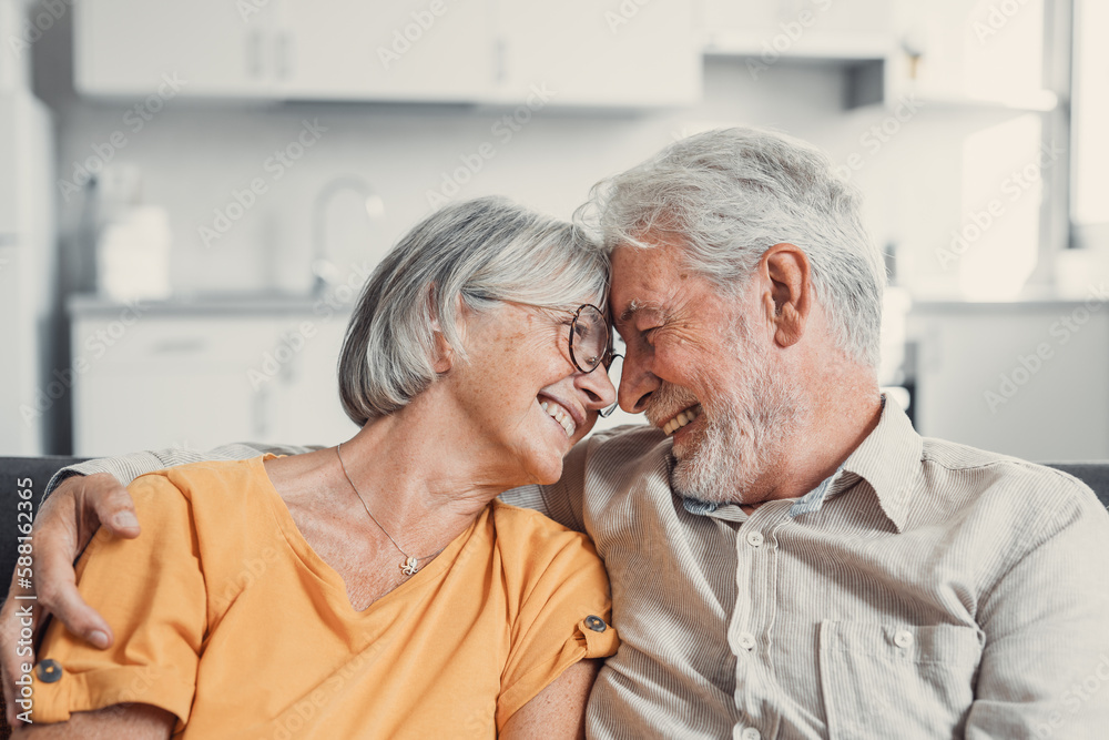 Happy laughing older married couple talking, laughing, standing in home interior together, hugging with love, enjoying close relationships, trust, support, care, feeling joy, tenderness. Happy laughing older married couple talking, laughing, standing in home interior together, hugging with love, enjoying close relationships, trust, support, care, feeling joy, tenderness.