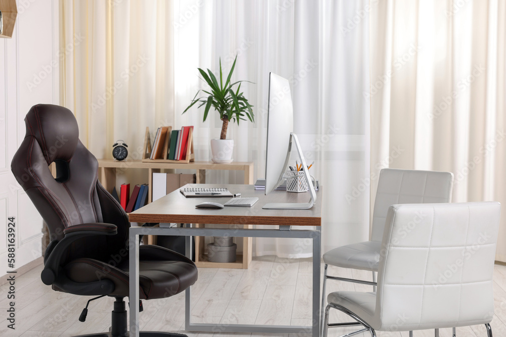Fototapeta premium Director's workplace with wooden table, computer and comfortable armchairs. Interior design