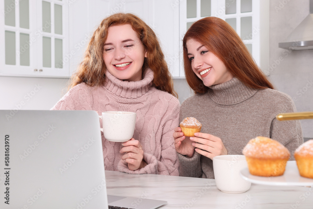 Beautiful young sisters spending time together in kitchen