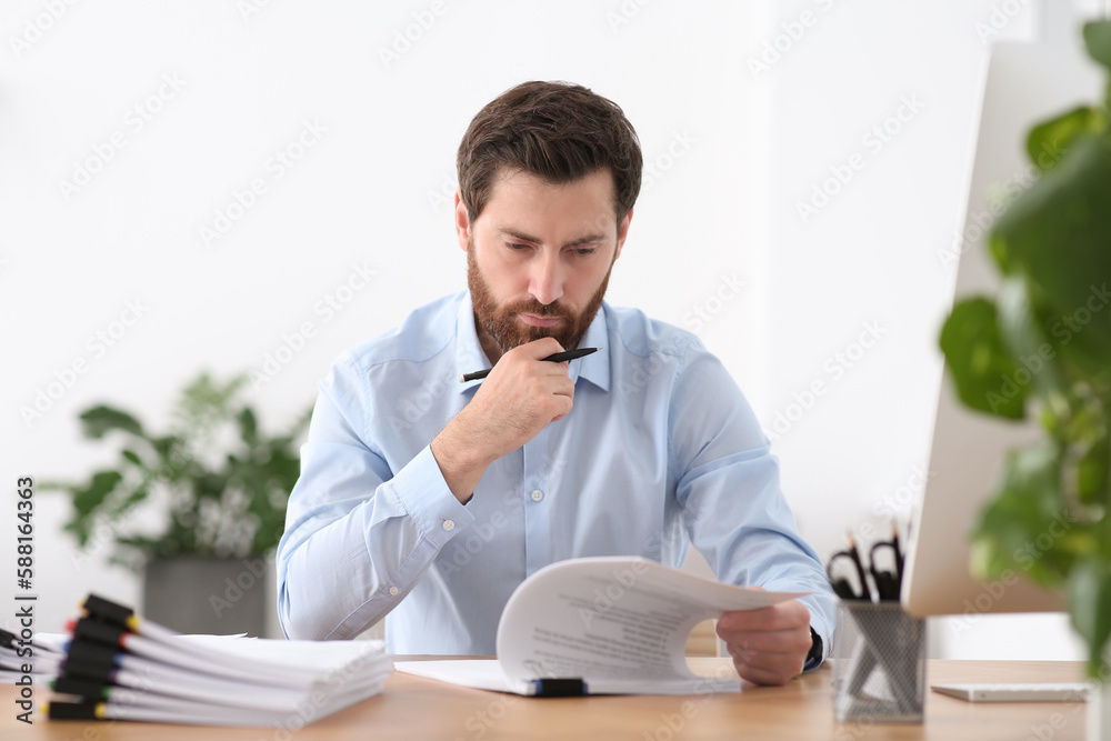 Naklejka premium Businessman working with documents at wooden table in office