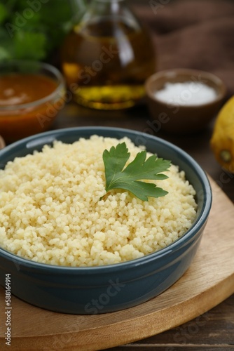 Tasty couscous with parsley on wooden table, closeup