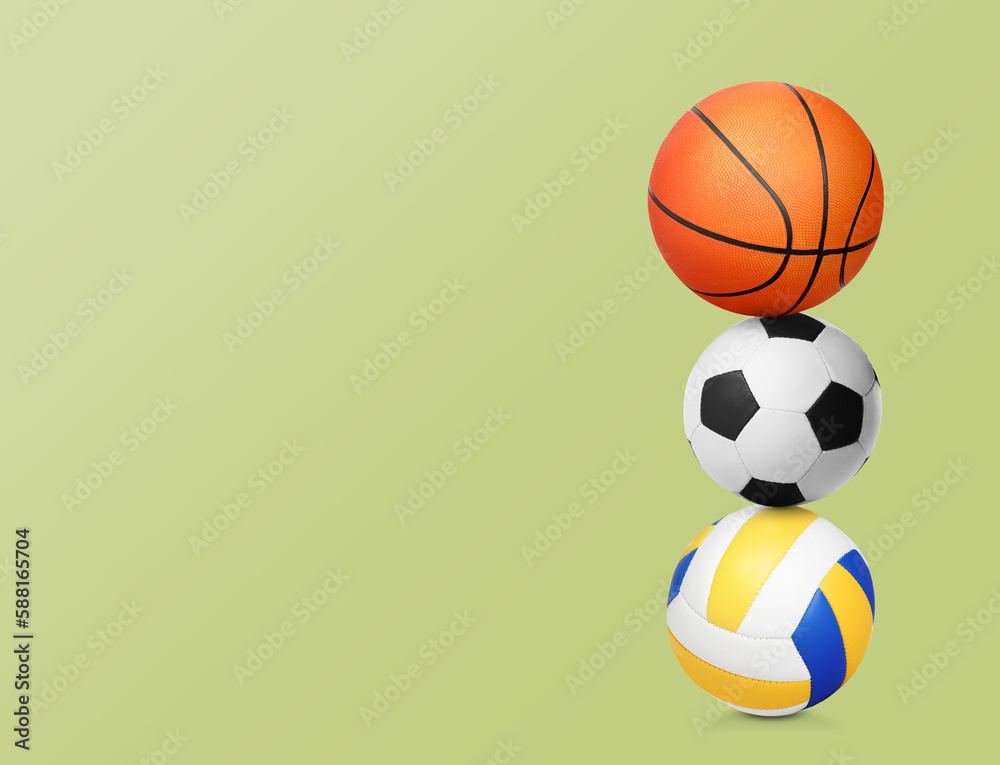 Stack of different sport balls on light yellow green background, space for text Stack of different sport balls on light yellow green background, space for text