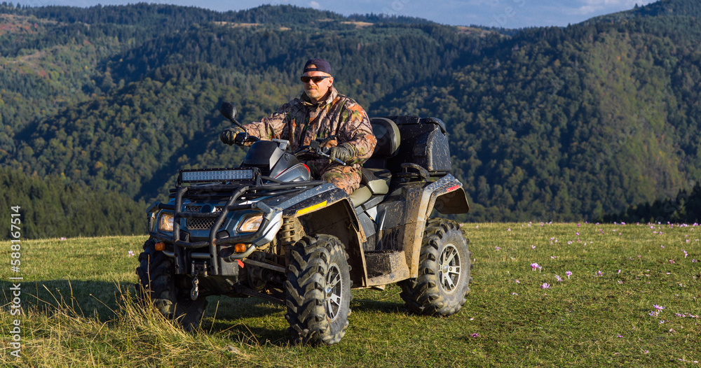 Obraz premium A man driving a quad ATV motorcycle through beautiful meadow landscapes