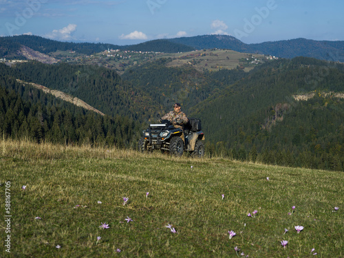 A man driving a quad ATV motorcycle through beautiful meadow landscapes