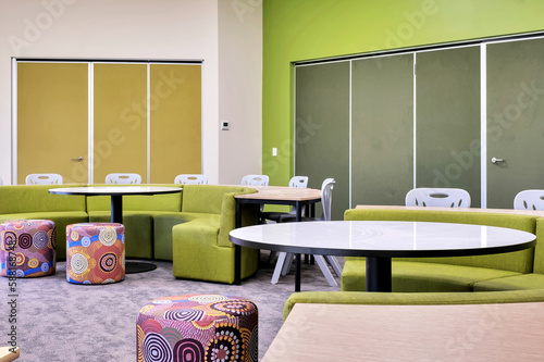 Modern school classroom with round and oval tables and curved sofas for students to sit and learn.