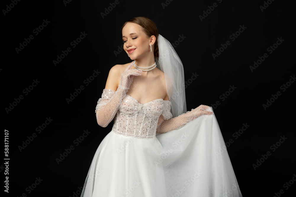 Close-up Portrait of a beautiful charming girl, the bride in a luxurious and elegant white wedding dress, poses and gesturing tenderly. Isolated on a black background.