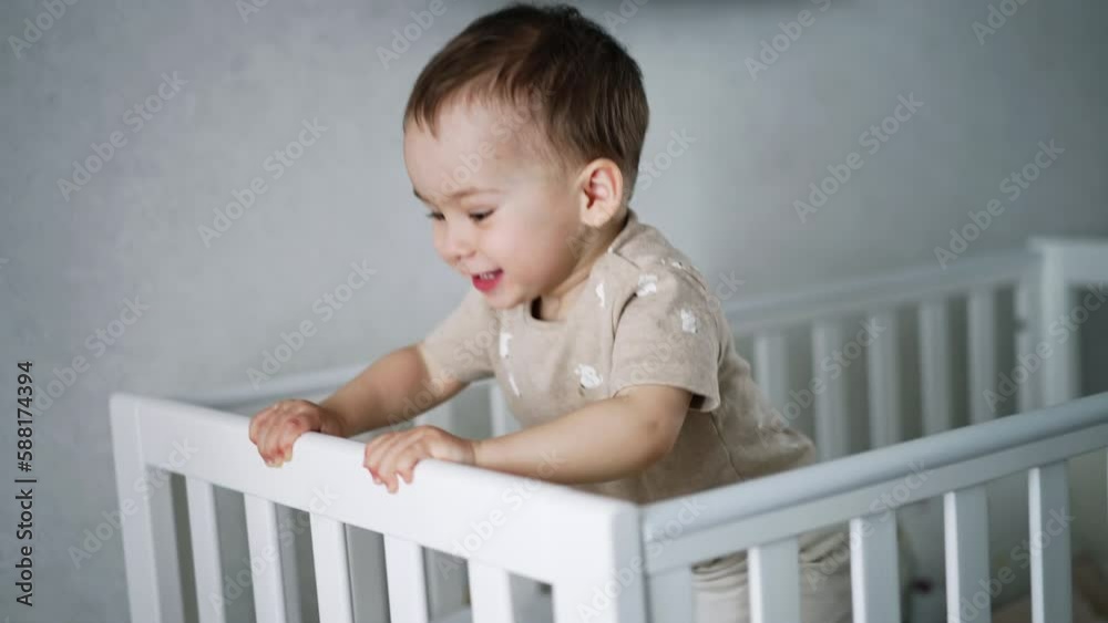 Cute lovely boy walks in his white crib. Playful child jumps to shake the bed. Baby at home. Cute lovely boy walks in his white crib. Playful child jumps to shake the bed. Baby at home.