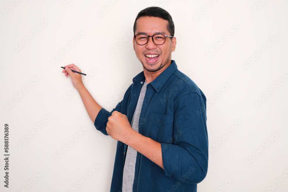 Asian man clenched fist showing excitement while writing something on white space behind Asian man clenched fist showing excitement while writing something on white space behind