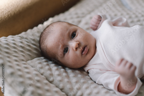 Portrait of a 1 month old baby. Cute newborn baby lying on a developing rug. Love baby. Newborn baby and mother. photo