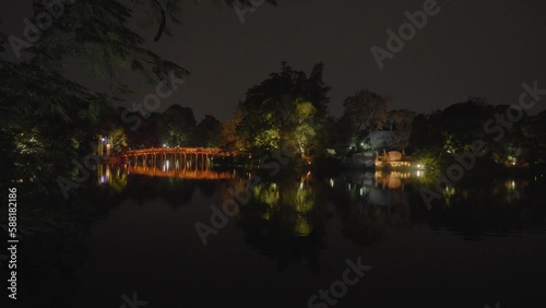Thê Húc Bridge illuminated at night over Hoàn Kiếm Lake in Hanoi, Vietnam. Pan right shot. photo