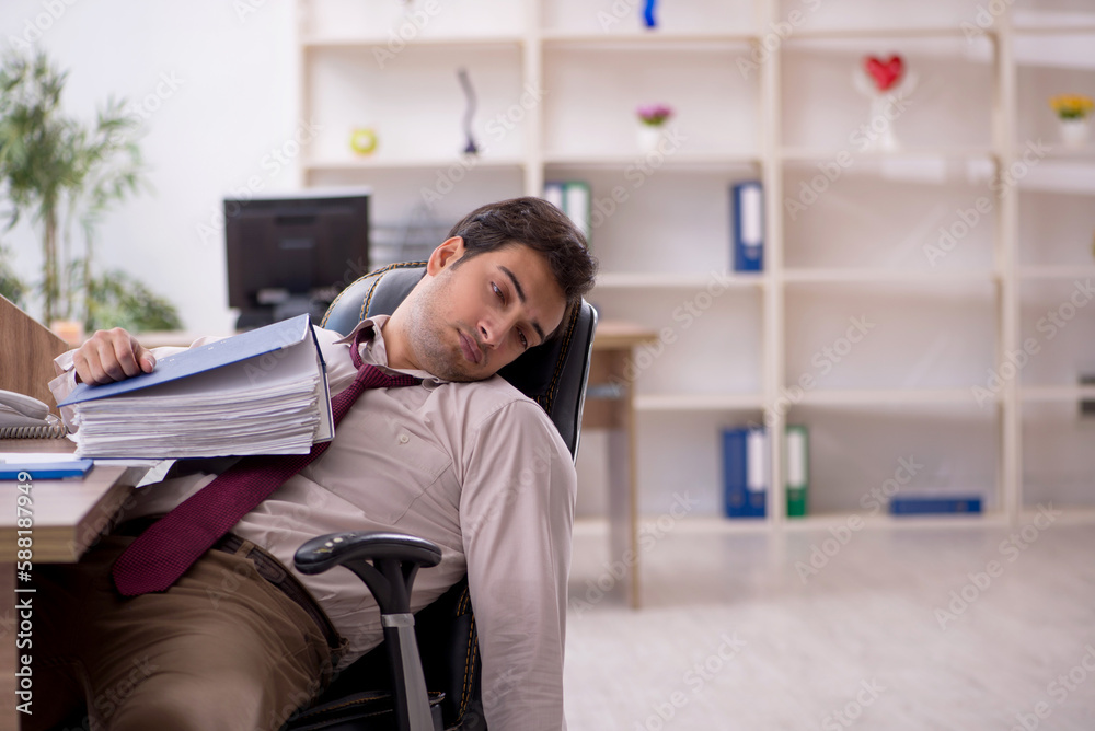 Young male employee and too much work in the office Young male employee and too much work in the office