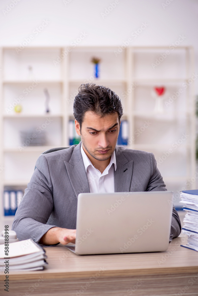 Young male employee and too much work in the office Young male employee and too much work in the office