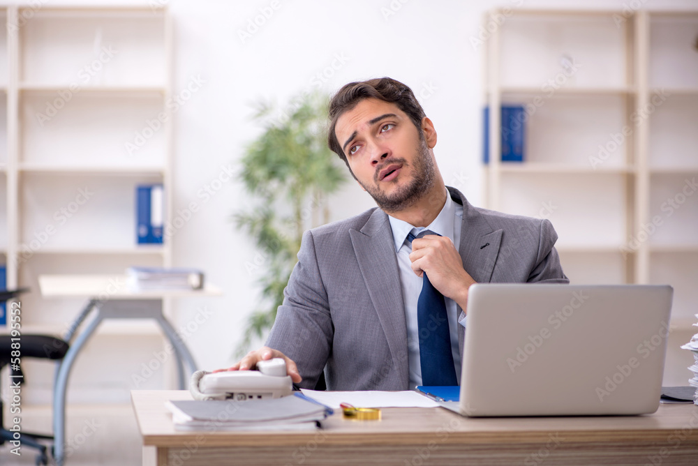 Young male employee and too much work in the office