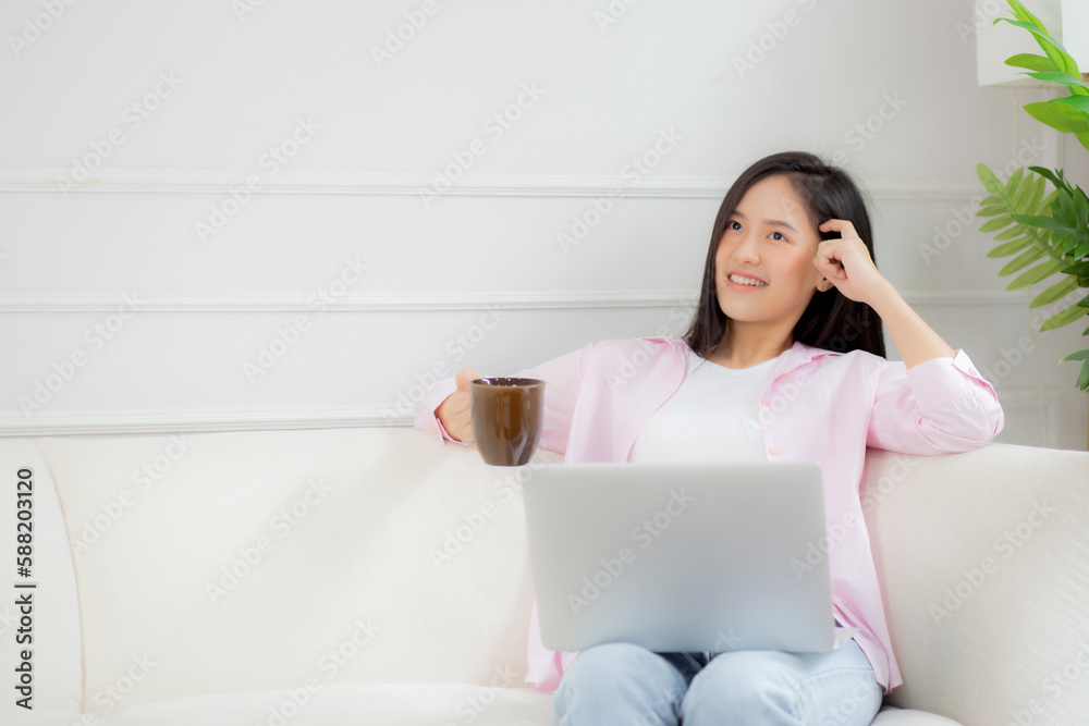 Young asian business woman work from home with laptop computer and drinking coffee on sofa in living room, freelance girl using notebook sitting on couch with comfort and relax, lifestyles concept. Young asian business woman work from home with laptop computer and drinking coffee on sofa in living room, freelance girl using notebook sitting on couch with comfort and relax, lifestyles concept.