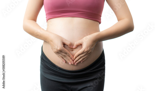Close up of the happy pregnant woman in fitness clothes using her hands to make a heart shape over her exposed belly