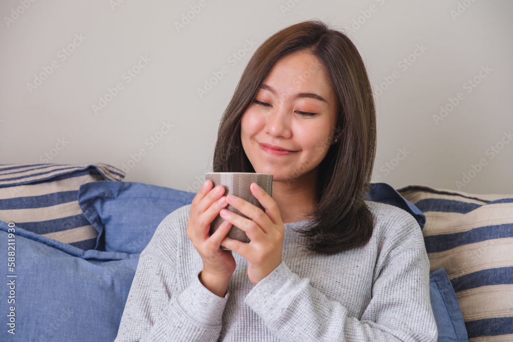 Portrait image of a young woman holding and drinking hot coffee at home Portrait image of a young woman holding and drinking hot coffee at home