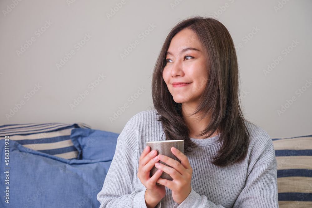 Portrait image of a young woman holding and drinking hot coffee at home Portrait image of a young woman holding and drinking hot coffee at home