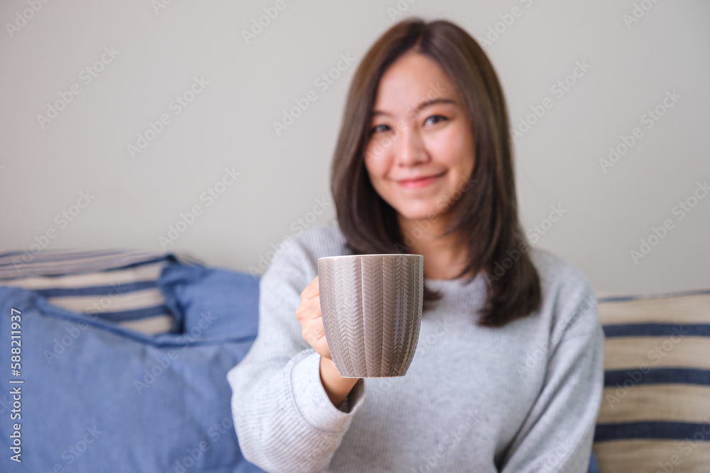 Portrait image of a young woman holding and serving a cup of hot coffee at home Portrait image of a young woman holding and serving a cup of hot coffee at home