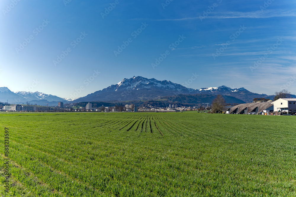 Scenic landscape and Swiss Alps with agriculture field and mount Pilatus seen from City of Emmen, Canton Lucerne, on a sunny spring day. Photo taken March 22nd, 2023, Emmen, Switzerland.