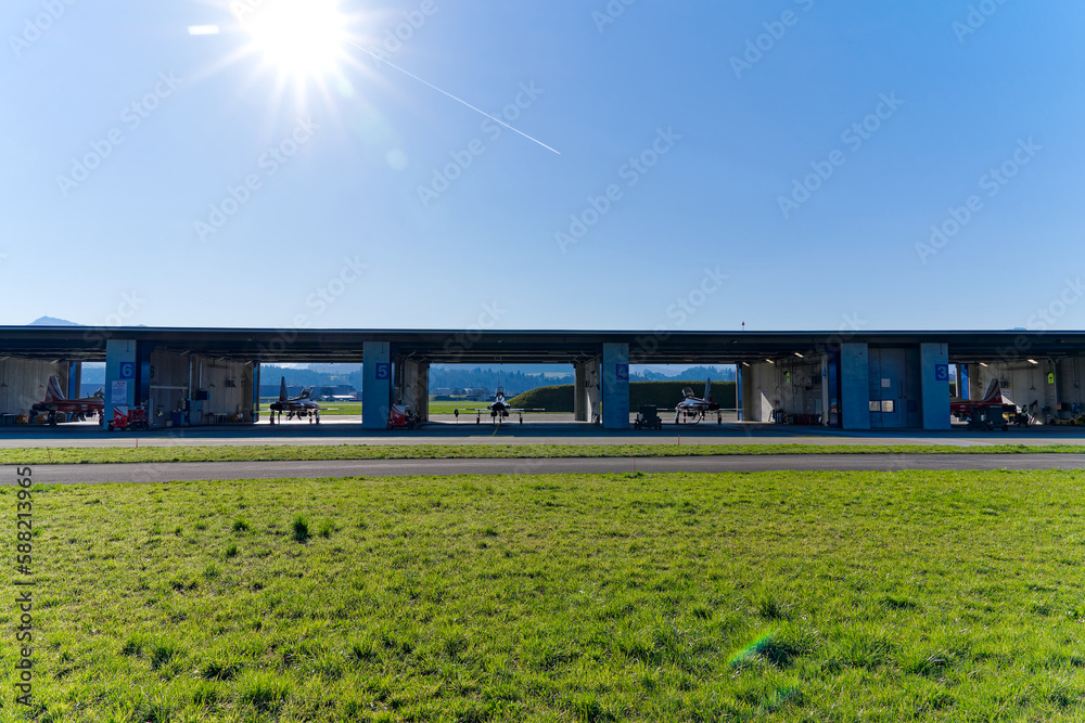 Fototapeta premium Red and white Northrop F-5E Tiger II fighters of Patrouille Suisse at hangar at Swiss Air Force airbase Emmen, Canton Lucerne, on a sunny spring day. Photo taken March 22nd, 2023, Emmen, Switzerland.