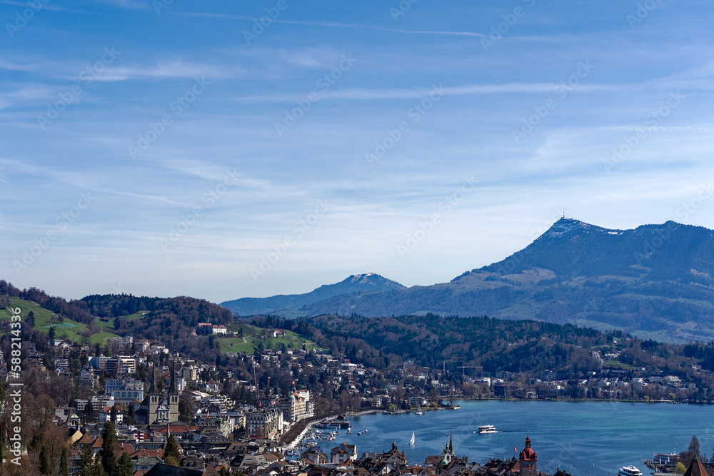 Fototapeta premium Aerial view of famous Swiss City of Luzern with Reuss River, Chapel Bridge, Lake Lucerne and Swiss Alps on a sunny spring day. Photo taken March 22nd, 2023, Lucerne, Switzerland.