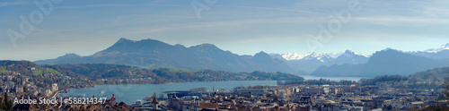 Wide angle aerial view of famous Swiss City of Luzern with Reuss River, Chapel Bridge, Lake Lucerne and Swiss Alps on a sunny spring day. Photo taken March 22nd, 2023, Lucerne, Switzerland.