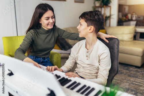 Brother and sister play electric piano at home and have fun.